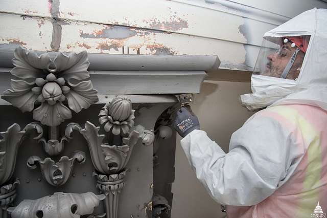 Man in protective gear removing lead paint from the US Capitol Dome.