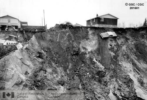 house sitting on edge of crater caused by a landslide. There is a car that looks like it slid about 24% of the way down the crater.