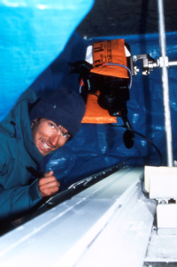 Man in a tent looking at an ice core. It looks like he is taking notes.