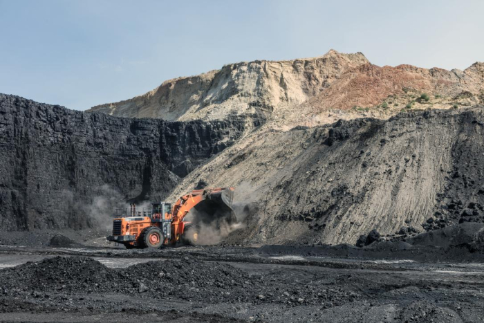 Huge excavator truck in a whole at the bottom of a coal mine. It is scrapping coal off the side.