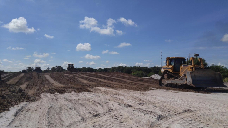 Bulldozers work to level and grade a large piece of cleared land